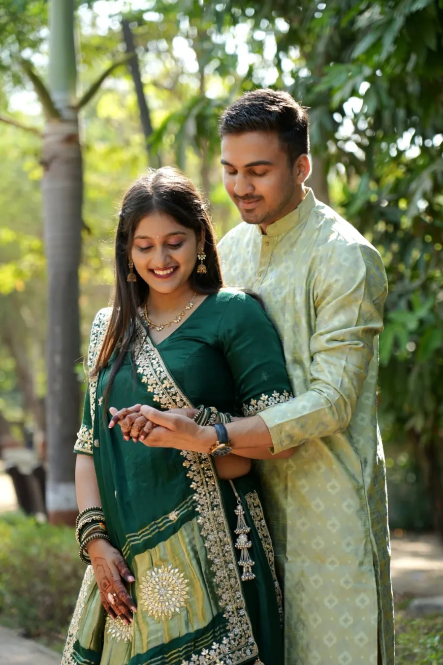 Neha in a green lehenga with Sahil's arms around her among the trees
