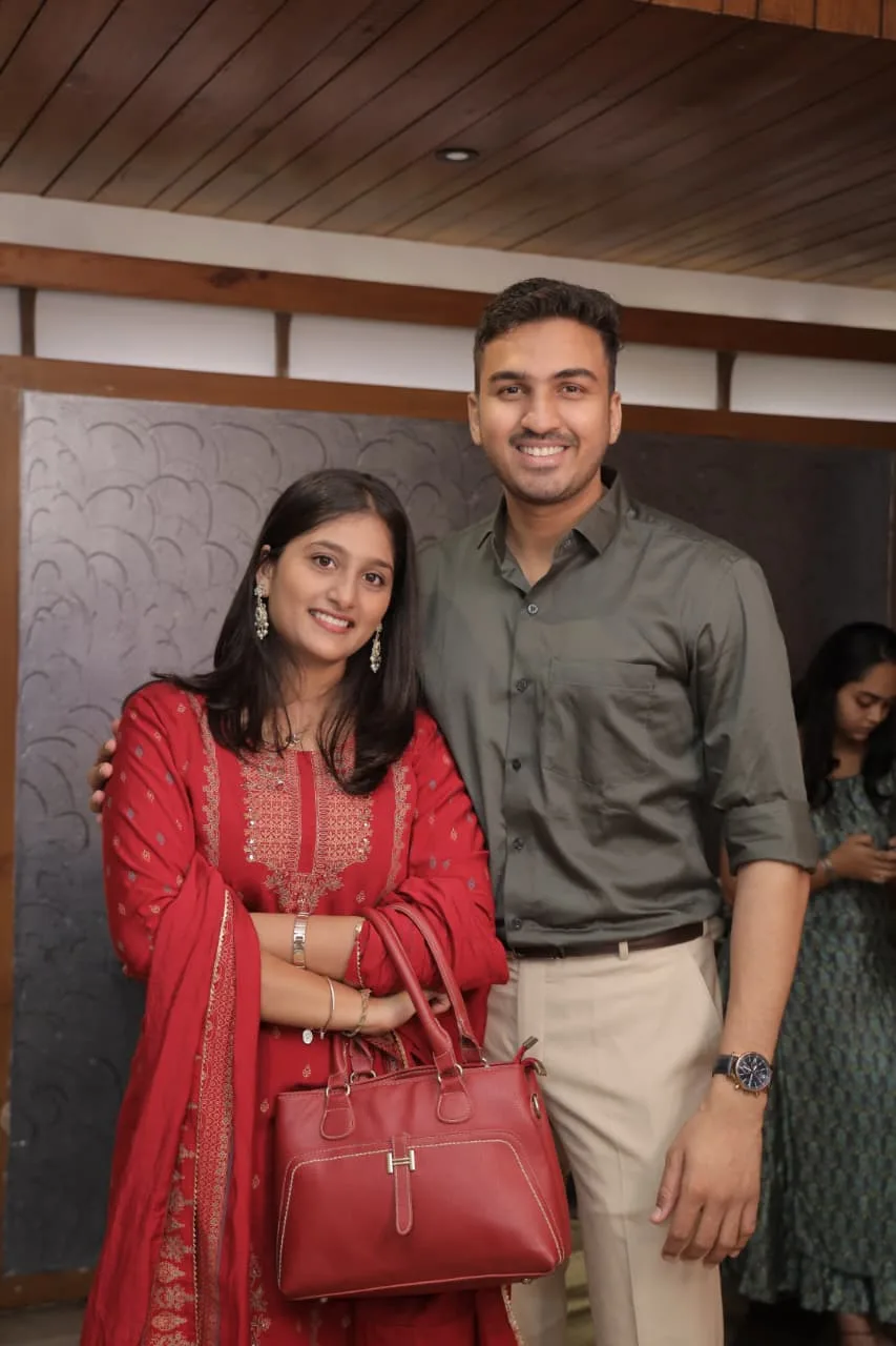 Neha in red and Sahil standing together, smiling